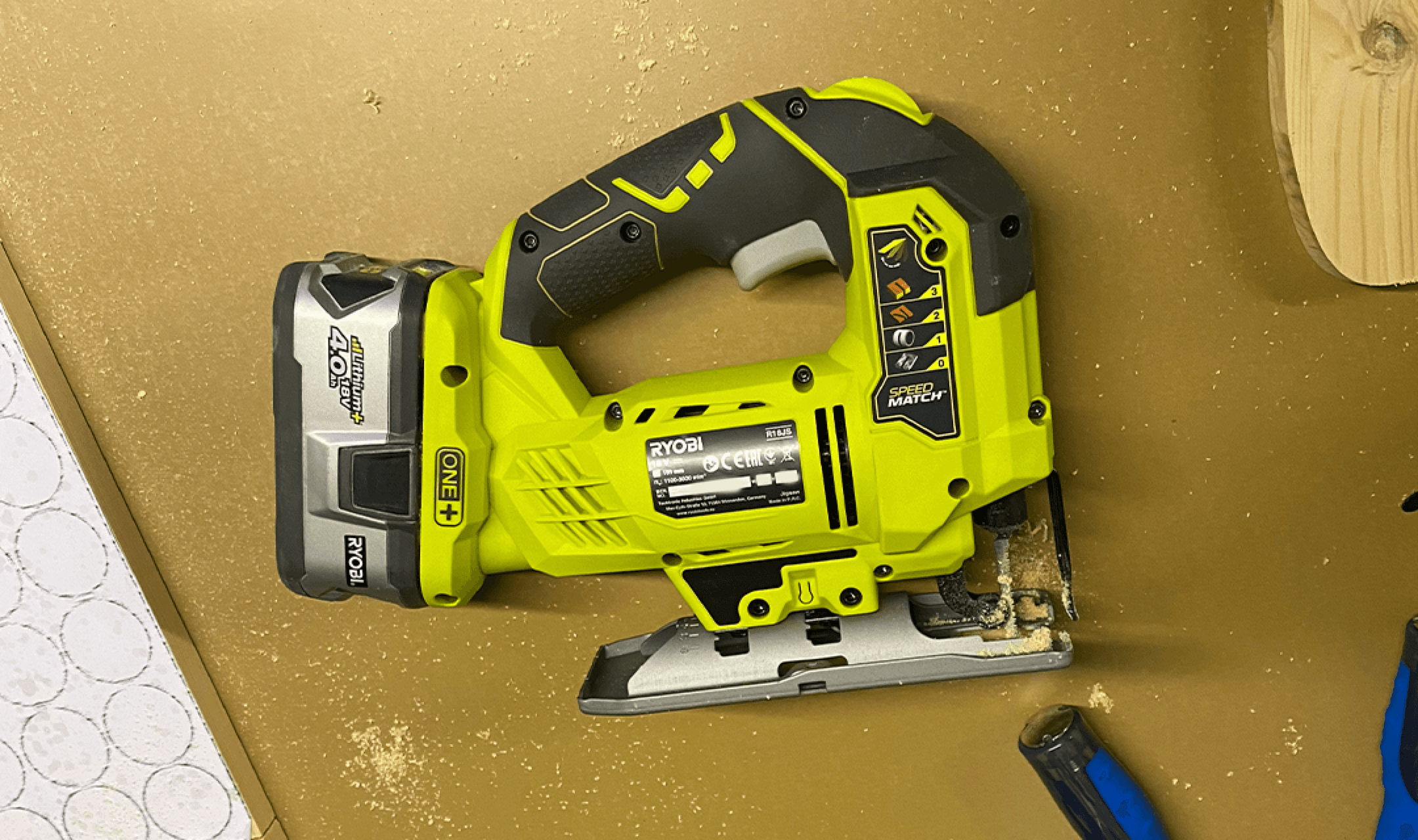 Ryobi cordless jigsaw resting on a brown board scattered with sawdust